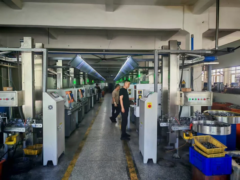 Workers in an aisle between rows of machining equipment at the GDQV factory