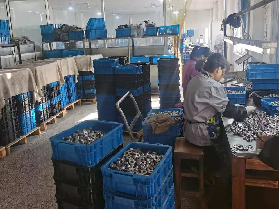 Worker checking bearings at a lit workbench at the GDQV factory